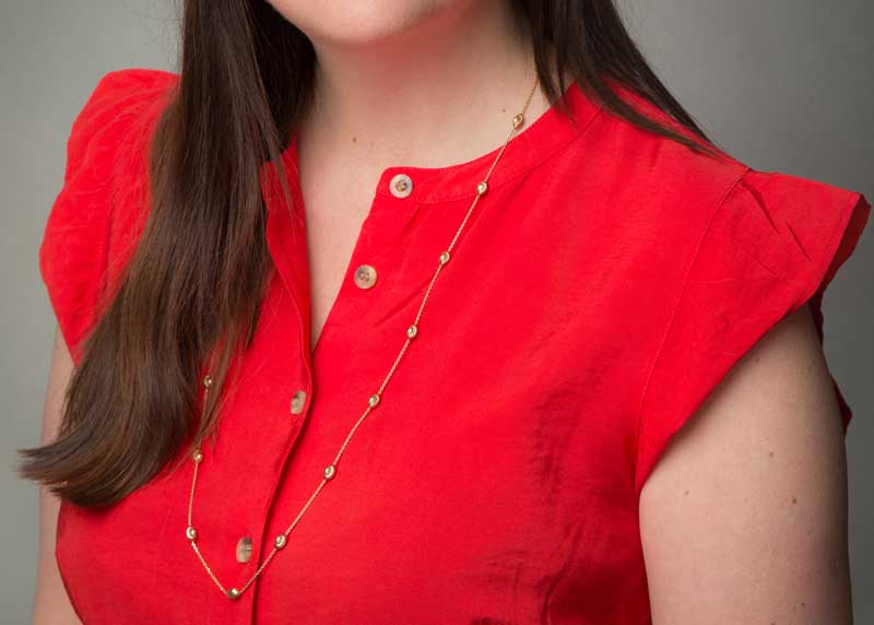 What to wear for a professional headshot. Red blouse with long gold chain.